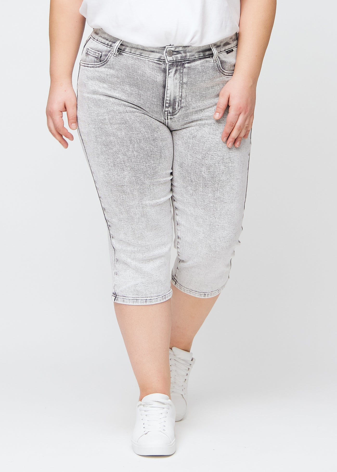 Lysegrå denim regular capris, modelnavn Ashes, som sidder lige til benet og slutter lige under knæet på en plus-size model, set forfra.