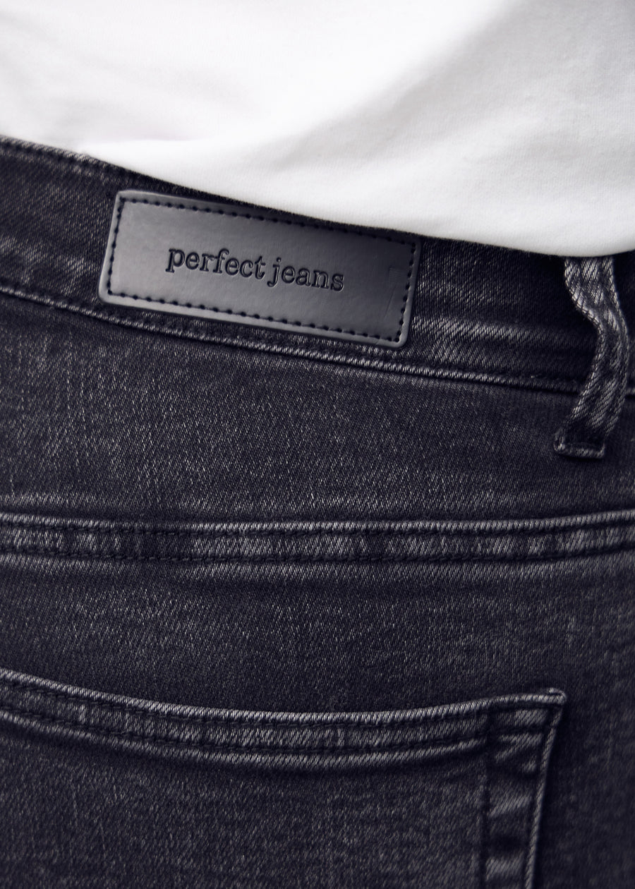 Close-up of dark grey denim with the Perfect Jeans leather patch at the back of the waistband.