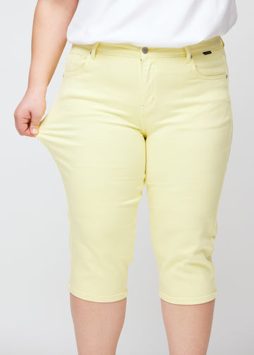 Plus-size model viser stretch ved at trække i caprisene ved låret – fokus på komfort og fleksibilitet.