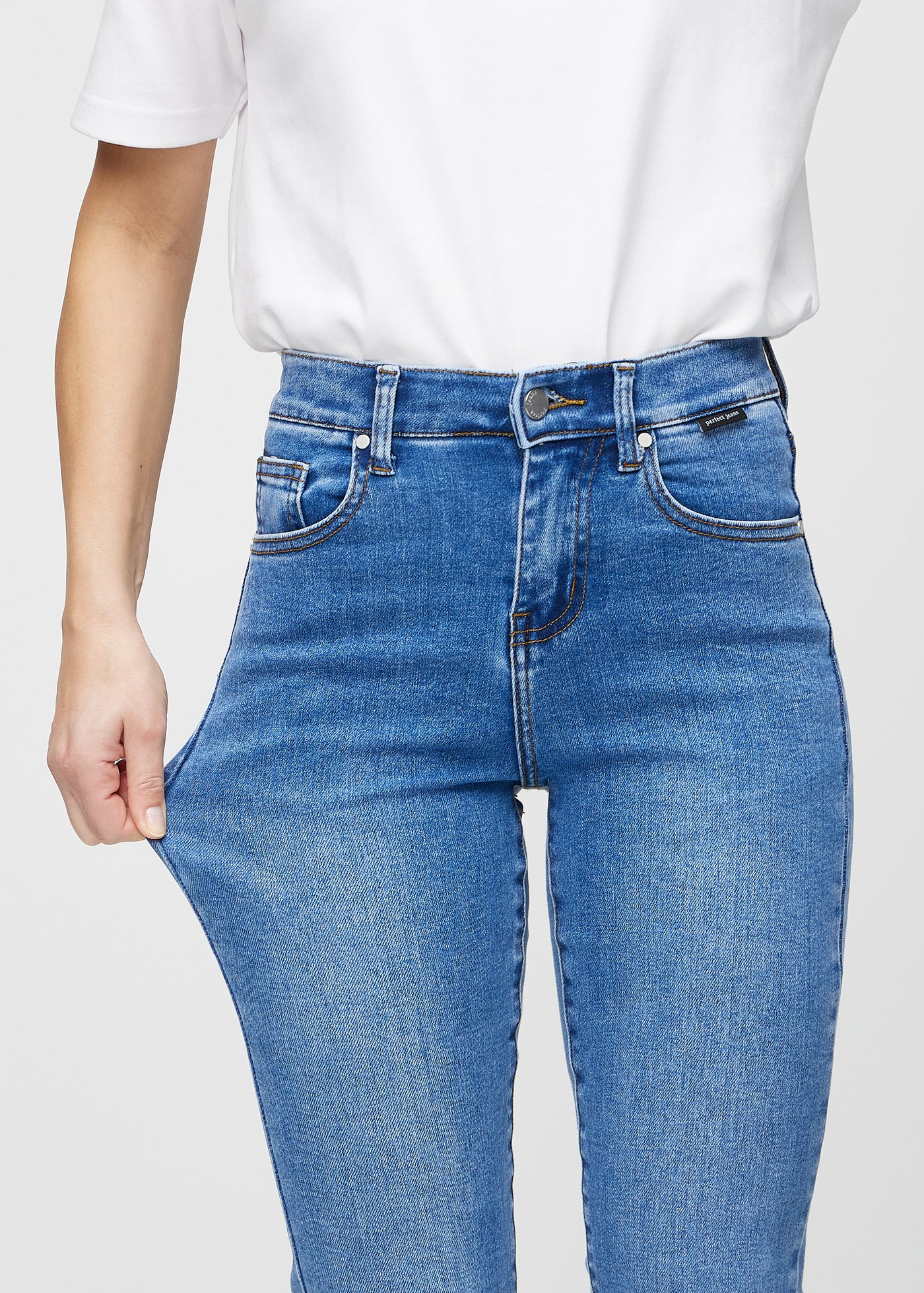 Model strækker jeansene ved låret for at vise stretch.