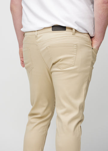 Beige slim jeans set bagfra tæt på en plus-size model for at vise detaljer.