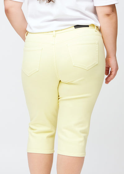 Tæt billede af bagdelen på en plus-size model i lysegule slim capris – detaljefokus på lommer og syninger.