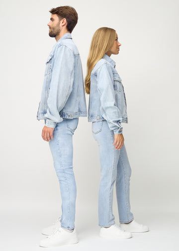 Lyseblå denim jakke i profil, set på afstand på mand og kvinde, viser jakken’s længde og pasform.