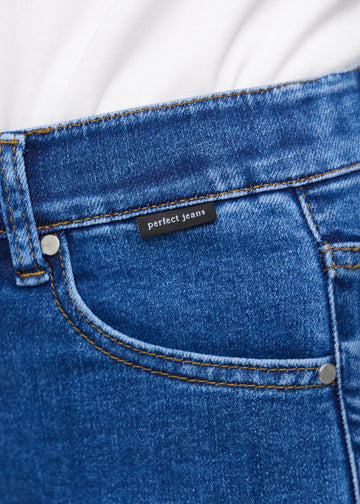 Nærbillede af mørkeblå denim med Perfect Jeans logoetiket ved forlommekanten.