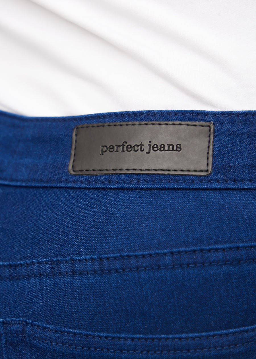 Nærbillede af mørkeblåt jeansmateriale med Perfect Jeans læderpatch bagpå i taljen, på en plus-size model.