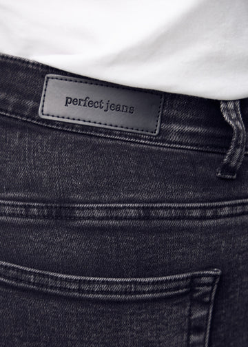 Nærbillede af mørkegrå denim med Perfect Jeans læderpatch bagpå i taljen.