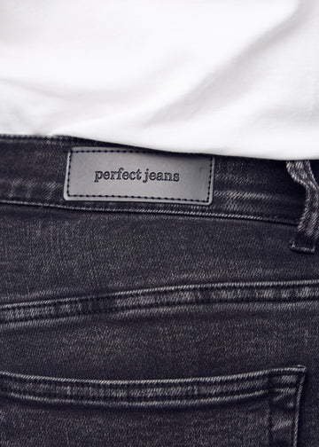 Nærbillede af mørkegrå denim med Perfect Jeans læderpatch bagpå i taljen, på en plus-size model.