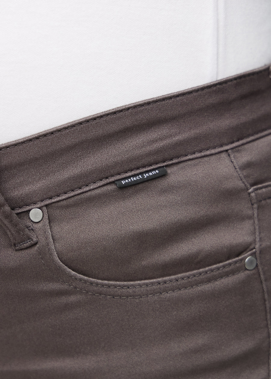Nærbillede af gråbrunt jeansmateriale med Perfect Jeans logoetiket ved forlommekanten, på en plus-size model.