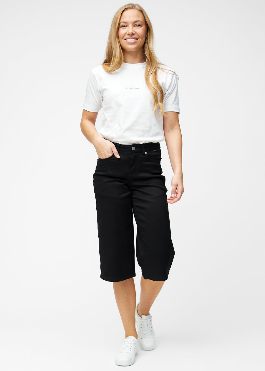 Fuldt billede af model i løse, sorte capris i farven Ravens, der går til lige under knæet.