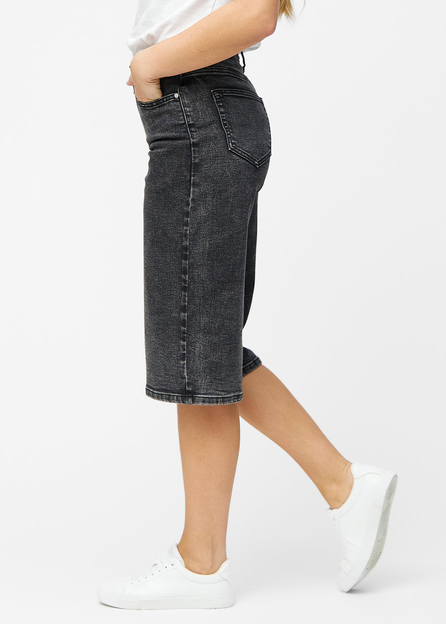 Løse, mørkegrå denim capris i farven Shadows set fra siden på model, hvor den brede pasform og længden til lige under knæet er synlig.