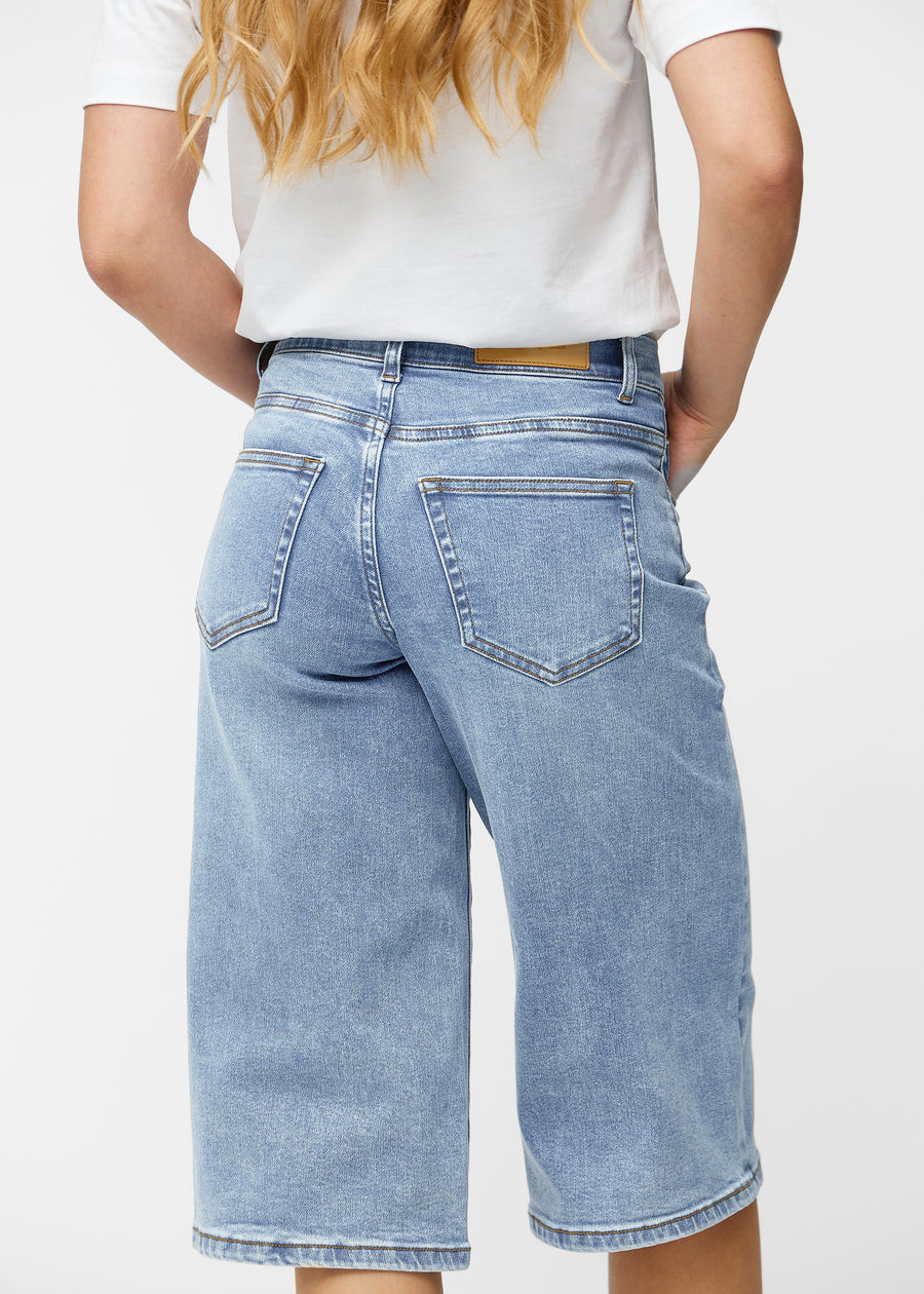 Loose, light blue denim capris in the colour Waves seen from the back up close to show fit and details.