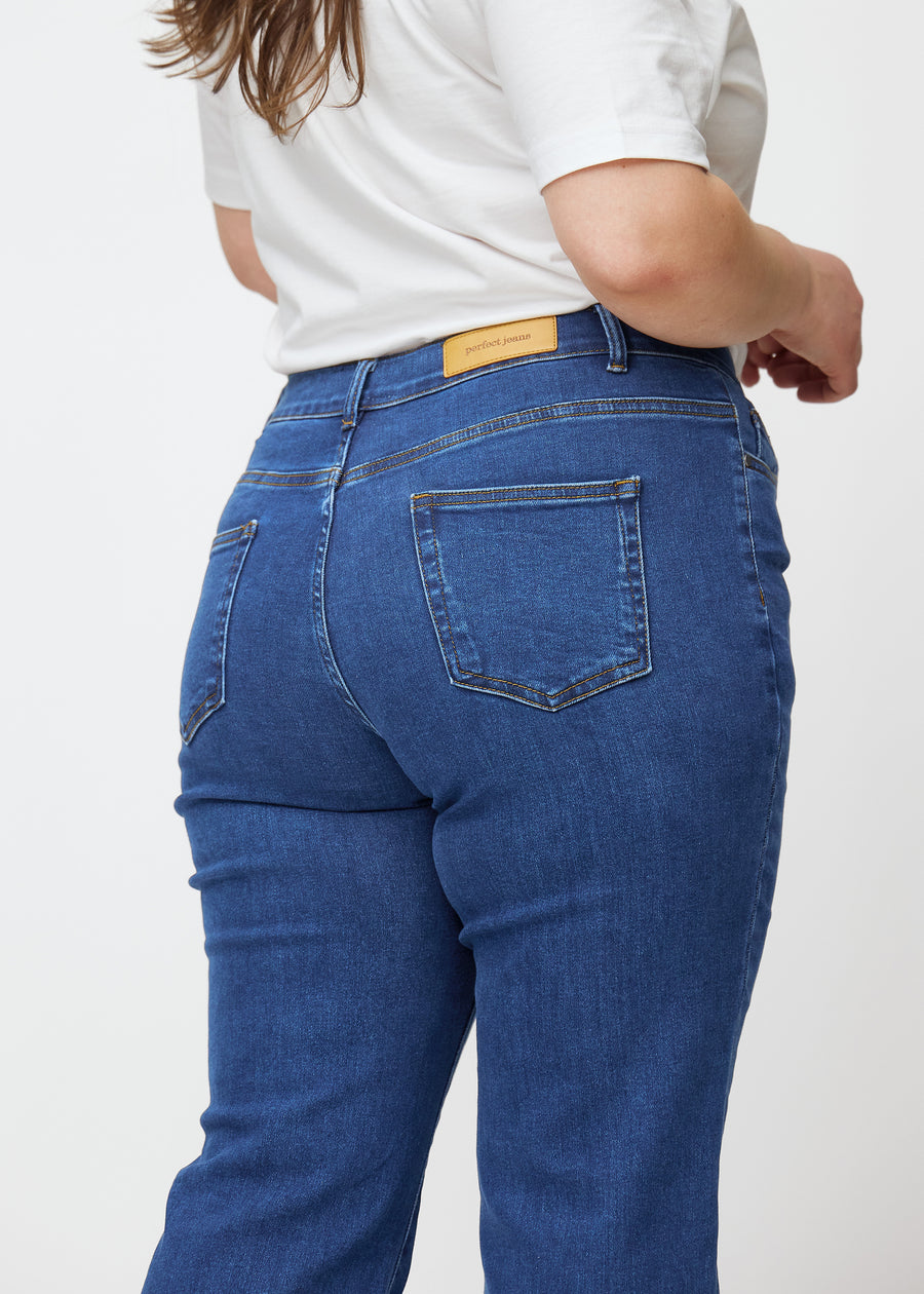 Mørkeblå mid-rise bootcut jeans i denimfarven Oceans set bagfra tæt på en plus-size model for at vise detaljer.