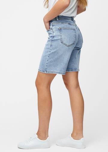 Loose, light blue denim shorts in the colour Waves seen from the side on a model, where the wide fit and length to just above the knee are visible.
