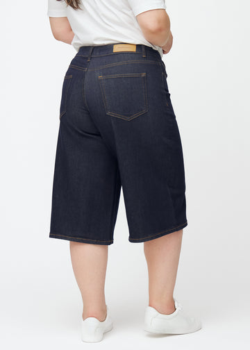 Deep dark blue denim capris for women in the colour Midnights seen from the back on a plus-size model.