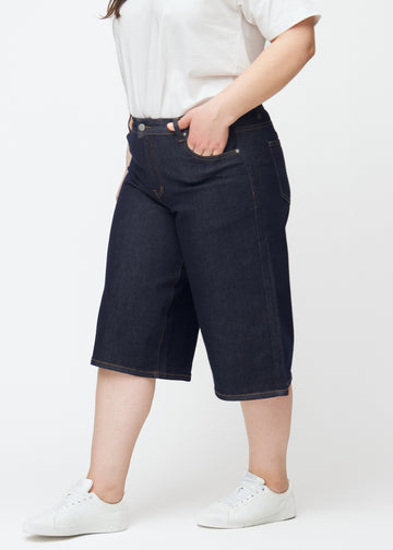 Deep dark blue denim capris for women in the colour Midnights with a loose fit seen from the side on a plus-size model.