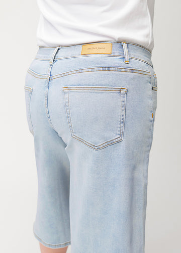 Close-up back view of loose, light blue Waves denim capris on a plus-size model, showing fit and details.