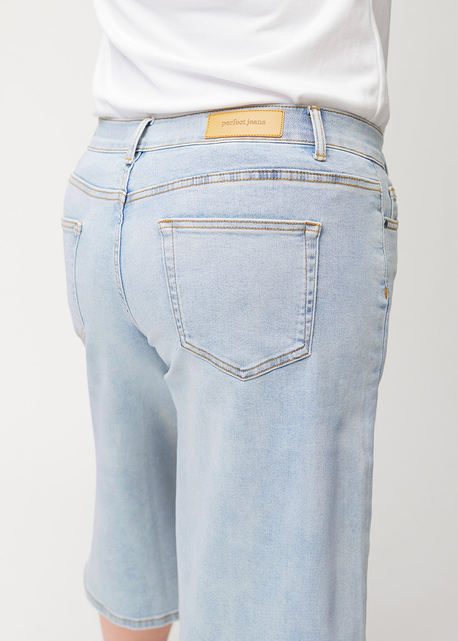 Close-up back view of loose, light blue Waves denim capris on a plus-size model, showing fit and details.