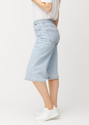 Side view of loose, light blue Waves denim capris on a model, showing the wide fit and length to just below the knee.