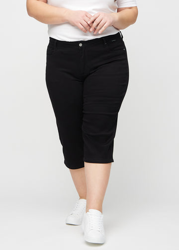 Black regular capris, model name Ravens, with a straight fit through the leg and ending just below the knee on a plus-size model, front view.