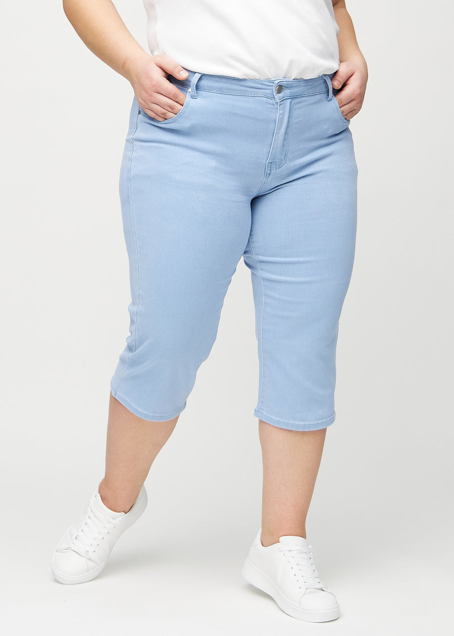 Light blue regular capris, model name Skies, with a straight fit through the leg and ending just below the knee on a plus-size model, seen from the front.