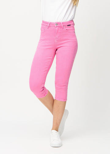 Skinny capris for women in pastel pink fabric, color Flamingos. Front view on a model, showing the close-fitting legs ending just below the knee.