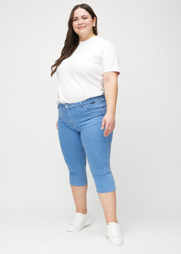 Full image of a plus-size model in blue skinny capris.