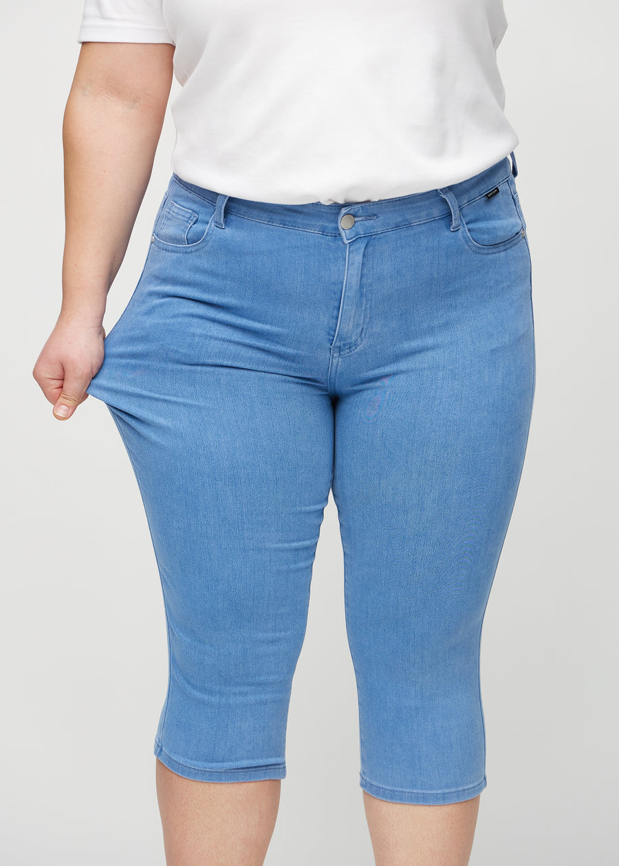 The plus-size model stretches the capris at the thigh to show the stretch.