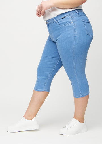 Blue skinny capris seen from the side on a plus-size model.