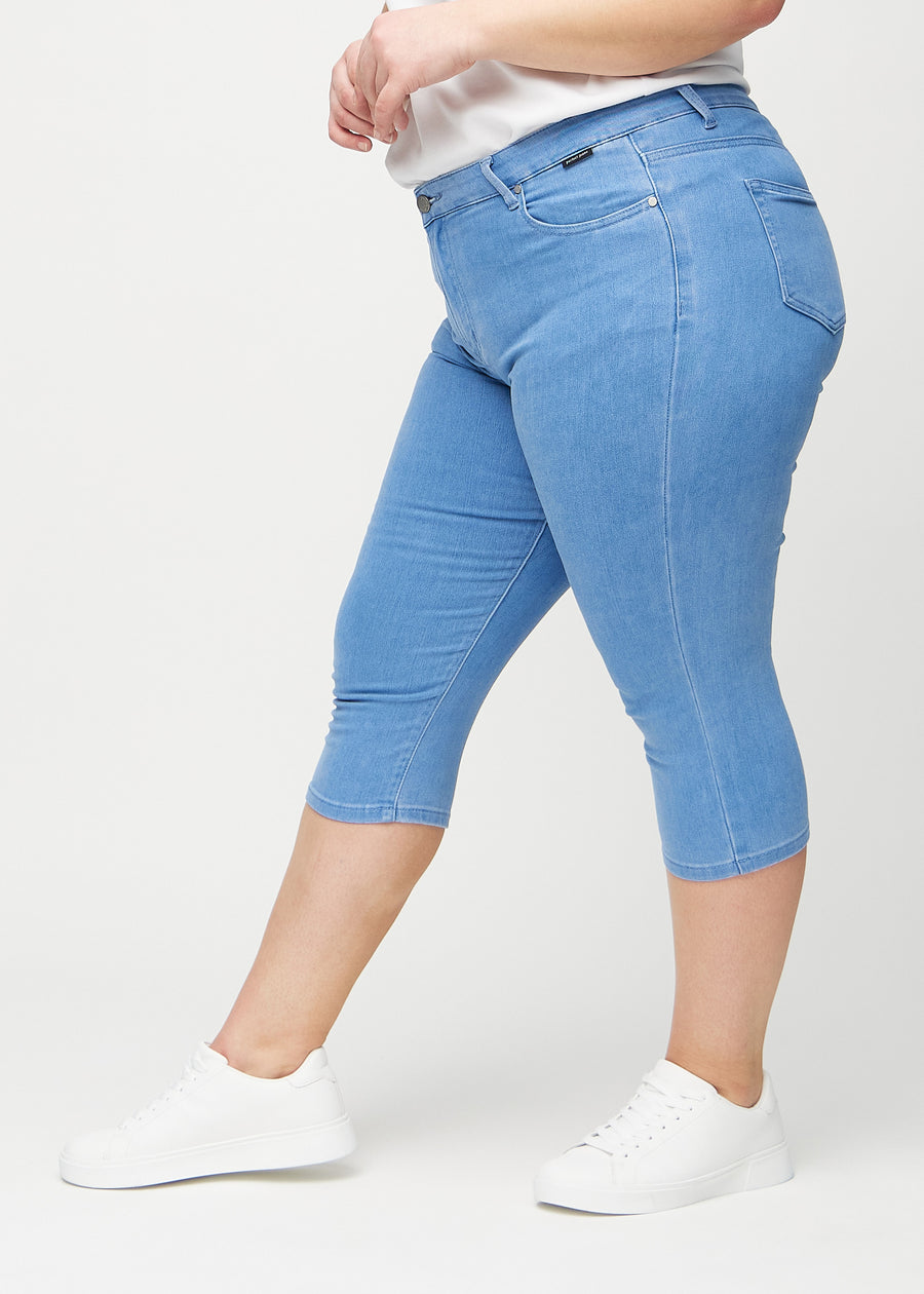 Blue skinny capris seen from the side on a plus-size model.