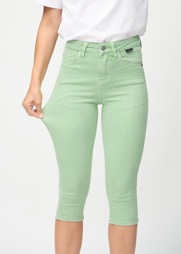 Skinny capris for women in pastel green fabric, color Mints. A model stretches the fabric to demonstrate its flexibility.