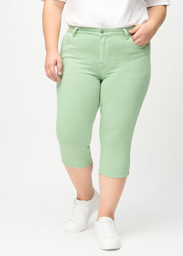 Skinny capris for women in pastel green fabric, color Mints. Front view on a plus-size model, showing the close-fitting legs ending just below the knee.