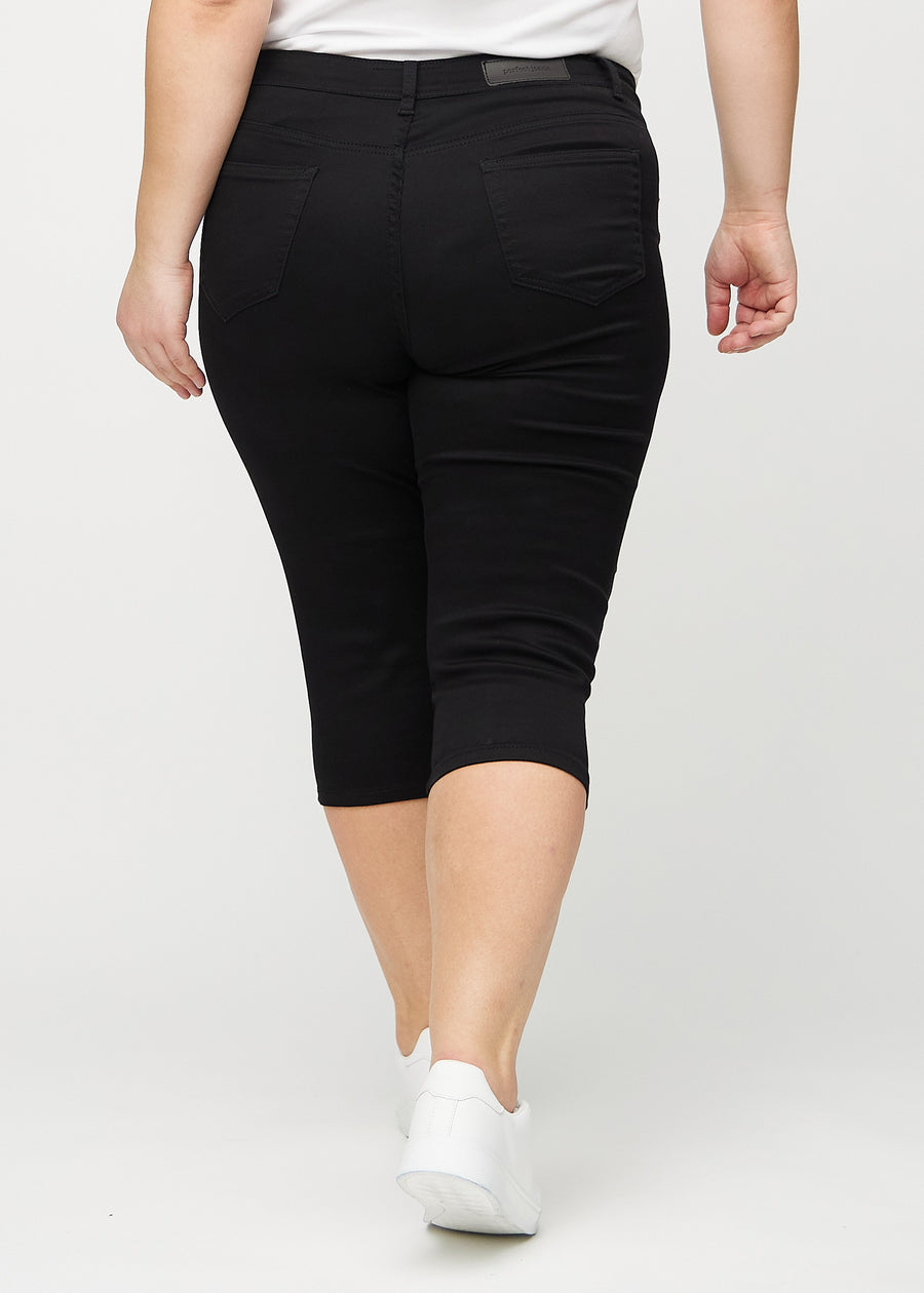 Black skinny capris seen from the back on a plus-size model, so the entire product can be seen.