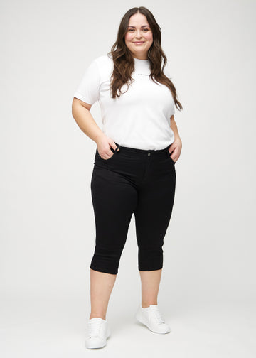 Full image of a plus-size model wearing black skinny capris.