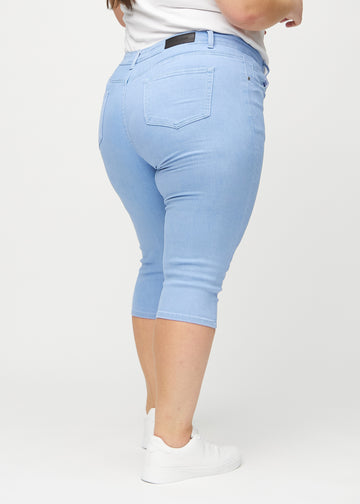Light blue skinny capris seen from the back on a plus-size model, so the entire product can be seen.