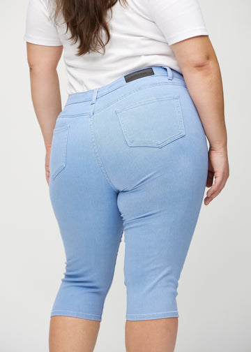 Light blue skinny capris seen from the back close up on a plus-size model to show details.