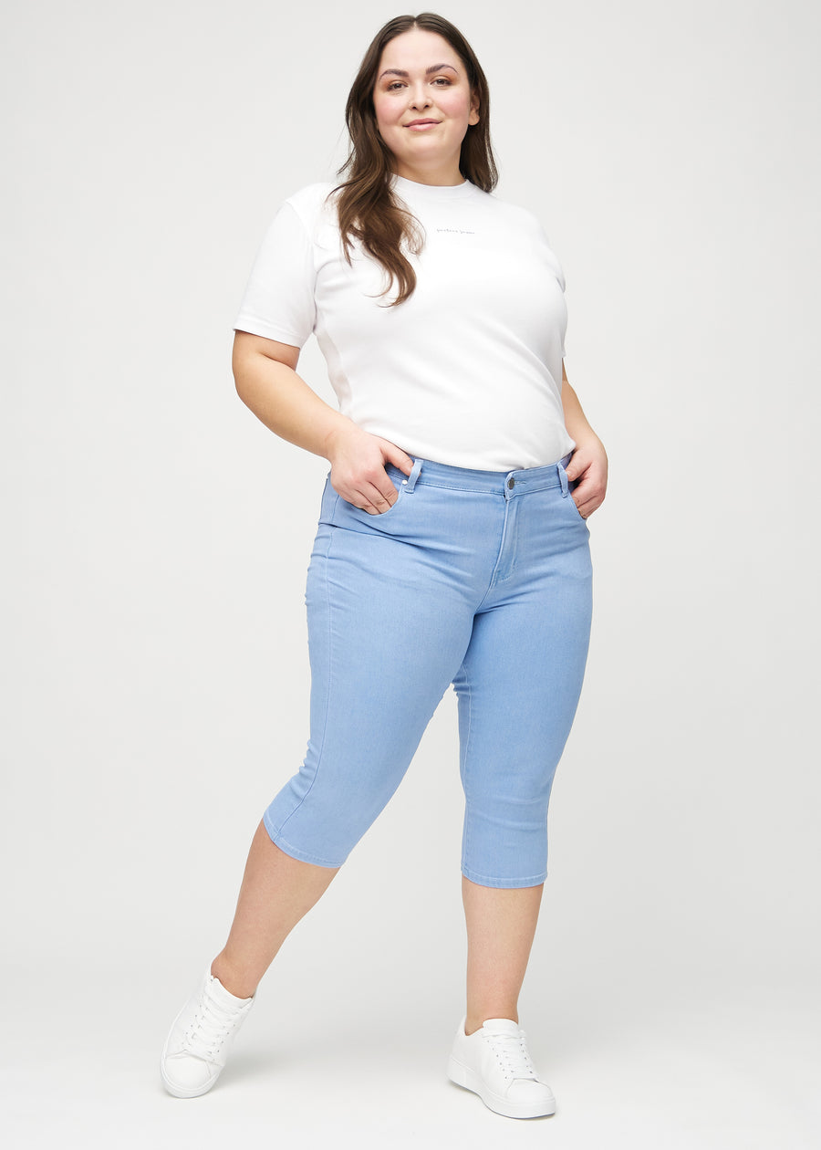 Full image of a plus-size model in light blue skinny capris.