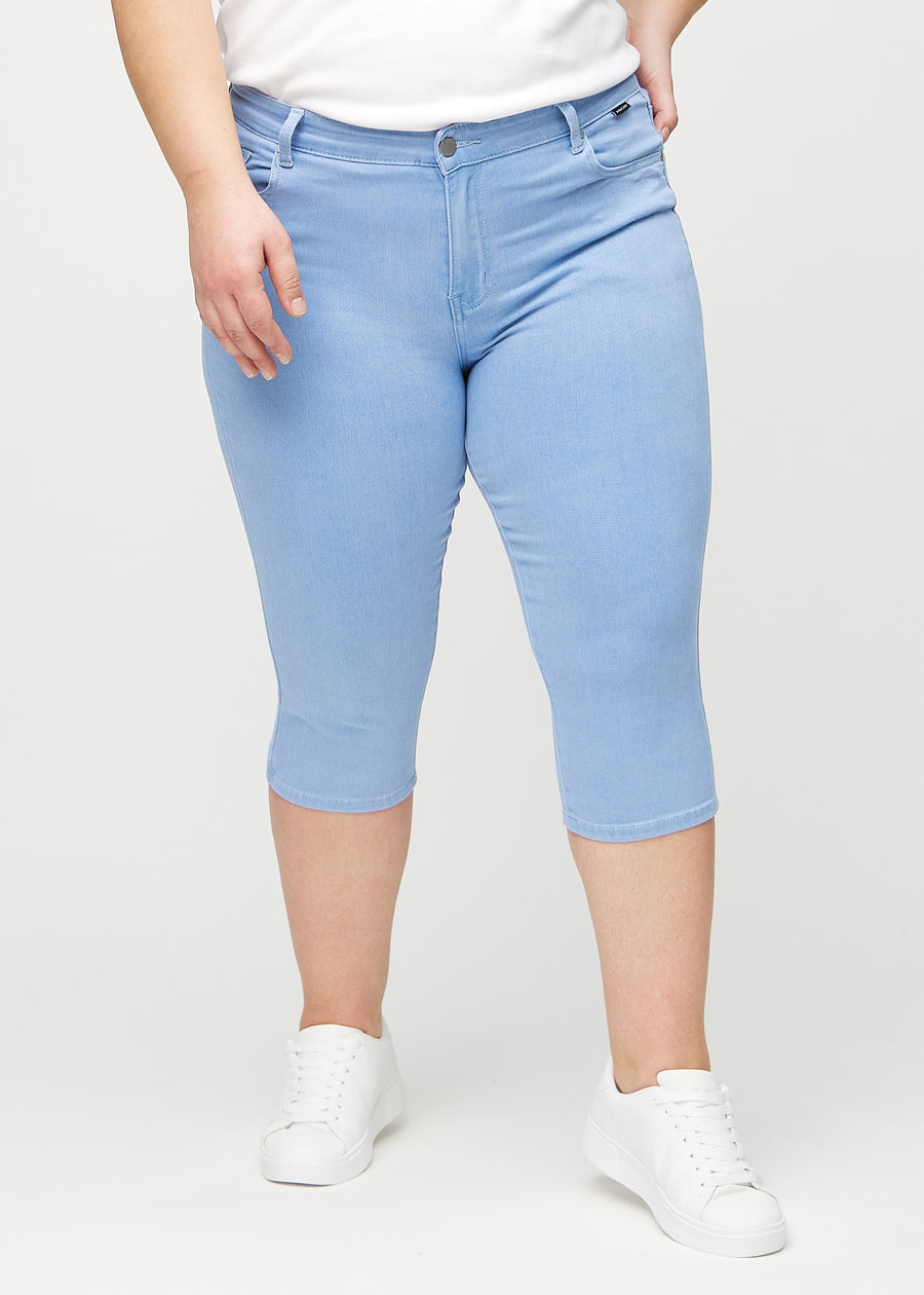 Light blue skinny capris, model name Skies, which fit closely to the leg and end just below the knee on a plus-size model, seen from the front.