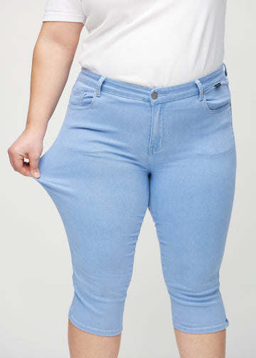 The plus-size model stretches the capris at the thigh to show the stretch.