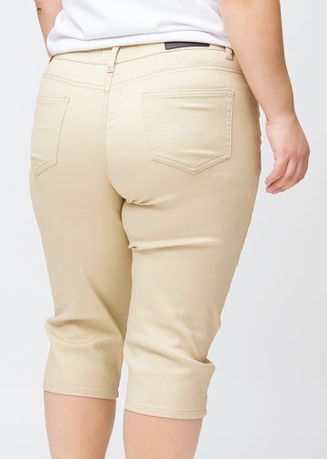Slim capris for women in beige jeans fabric, color Gazelles. Close-up from behind on a plus-size model, highlighting the back pockets and stitching.
