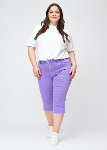 Slim capris for women in pastel purple jeans fabric, color Lavenders. Full-length view of a plus-size model wearing slim capris.