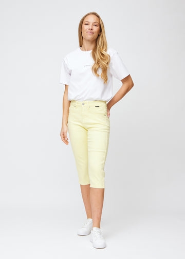 Slim capris for women in pastel light yellow jeans fabric, color Lemonades. Full-length view of a model wearing slim capris.