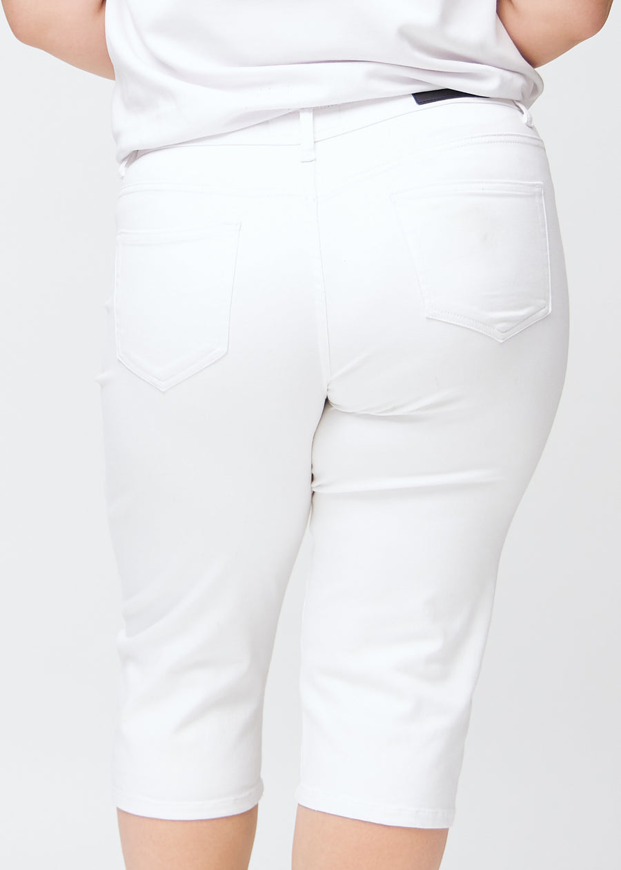 Close-up of the back on a plus-size model wearing white slim capris, detail focus on pockets and stitching.