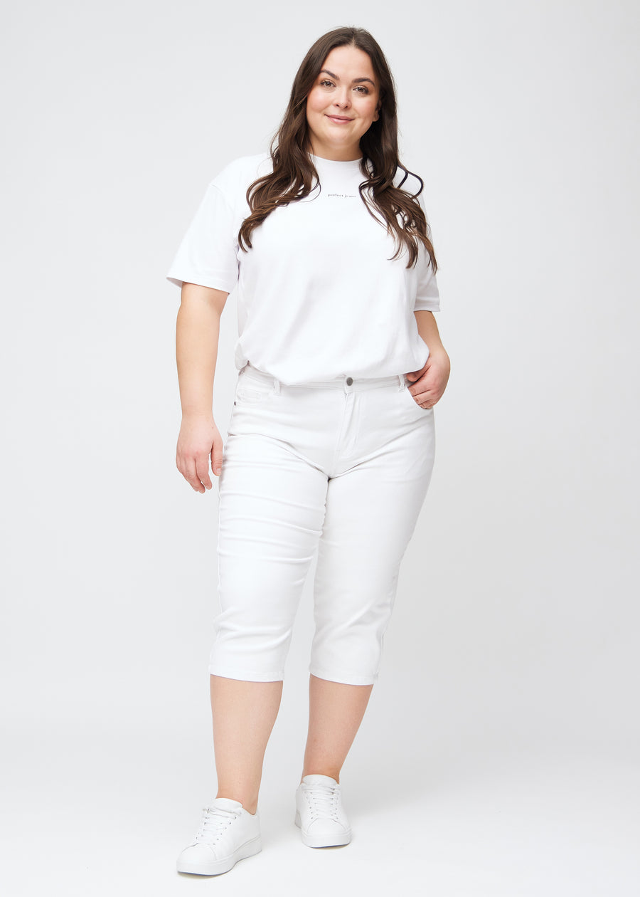 Full image of plus-size model wearing white slim capris.
