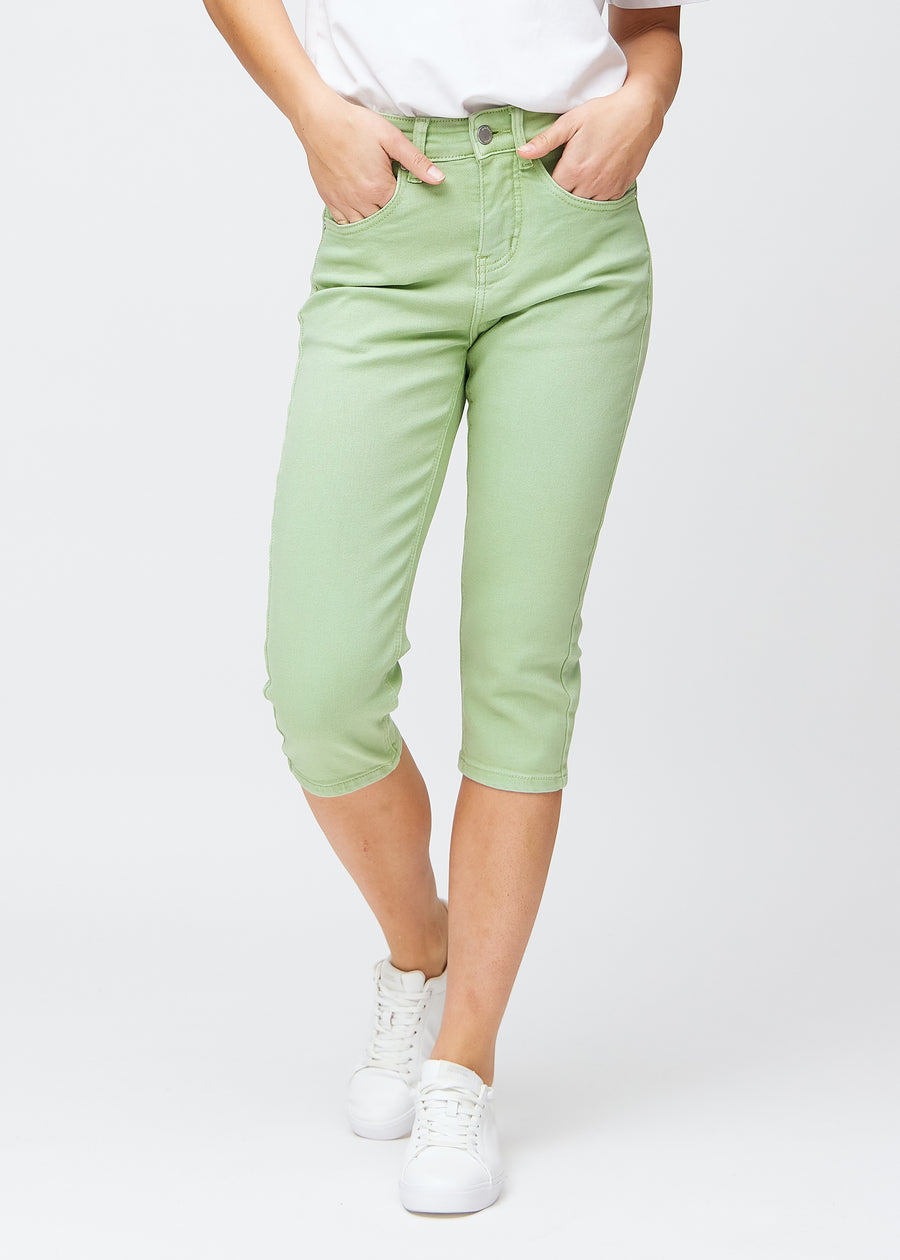 Slim capris for women in pastel light green jeans fabric, color Mints. Front view on a model, showing the fitted cut ending just below the knee.