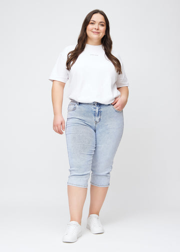 Slim capris for women in light blue denim, color Waves. Full-length view of a plus-size model wearing slim capris.