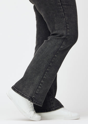 Dark grey mid-rise bootcut jeans in Shadows. Close-up of the ankle area on a plus-size model, showing the subtle bootcut flare.