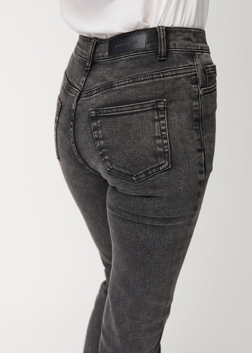 Dark grey mid-rise bootcut jeans in Shadows. Close-up back view on a model, showing the details.