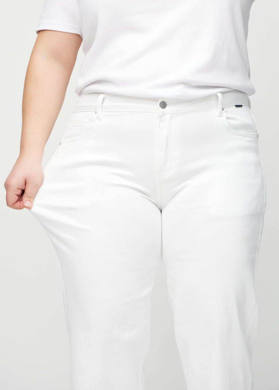 Loose jeans for women in white, color Marguerites. A plus-size model stretches the denim at the thigh to show the fabric&