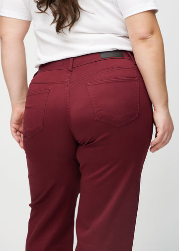 Loose jeans for women in dark red, color Santas. Close-up from behind on a plus-size model, showing the fit and details.