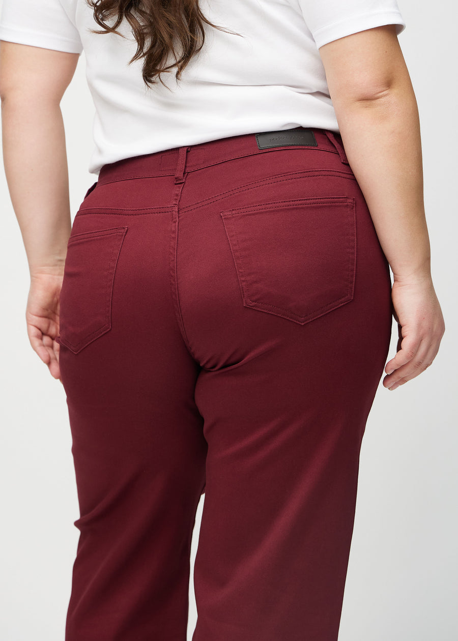 Loose jeans for women in dark red, color Santas. Close-up from behind on a plus-size model, showing the fit and details.